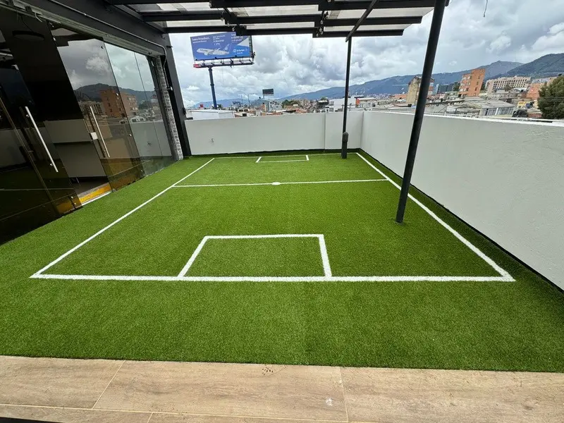 Fotografía de obra terminada: terraza con cancha sintética y comedor. Oficinas con zona recreativa en Bogotá, Decord Design